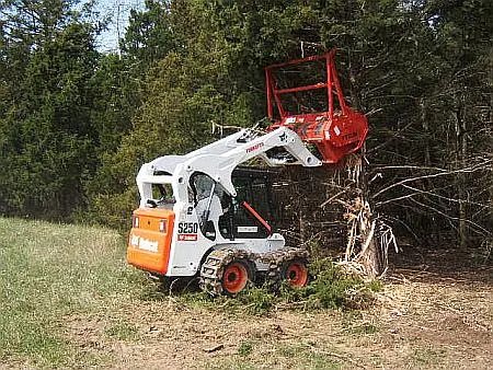 Skid steer with a mulching head pushing into brush